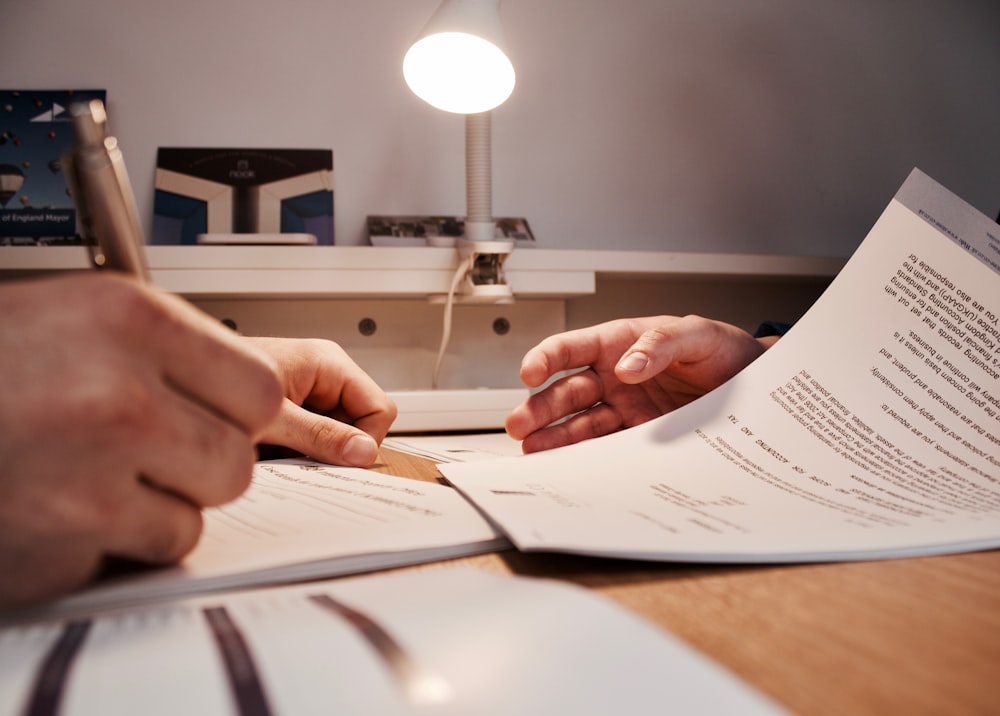 Close-up of hands reviewing financial documents with a sleek laptop in the background.