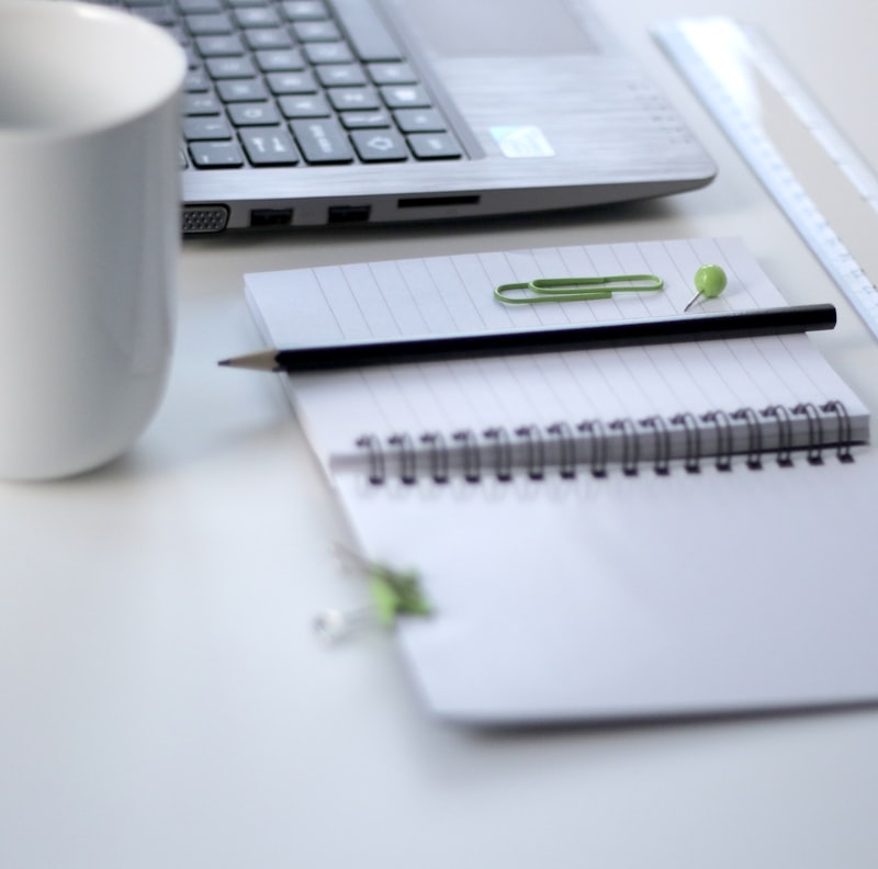 A clean, organized workspace with a notebook, pen, and a cup of coffee.