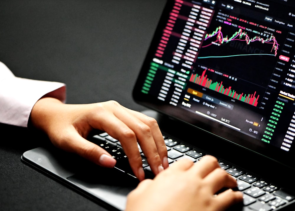Close-up of hands working on financial documents with a laptop in the background.